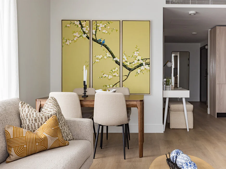 Contemporary dining area with wooden table, neutral chairs, and floral wall art in Regents View show home
