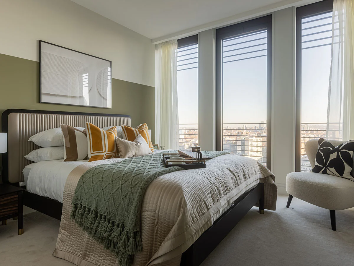 Modern furnished bedroom with home office desk in a West End Gate apartment, featuring neutral interiors, a double bed, and floor-to-ceiling windows.