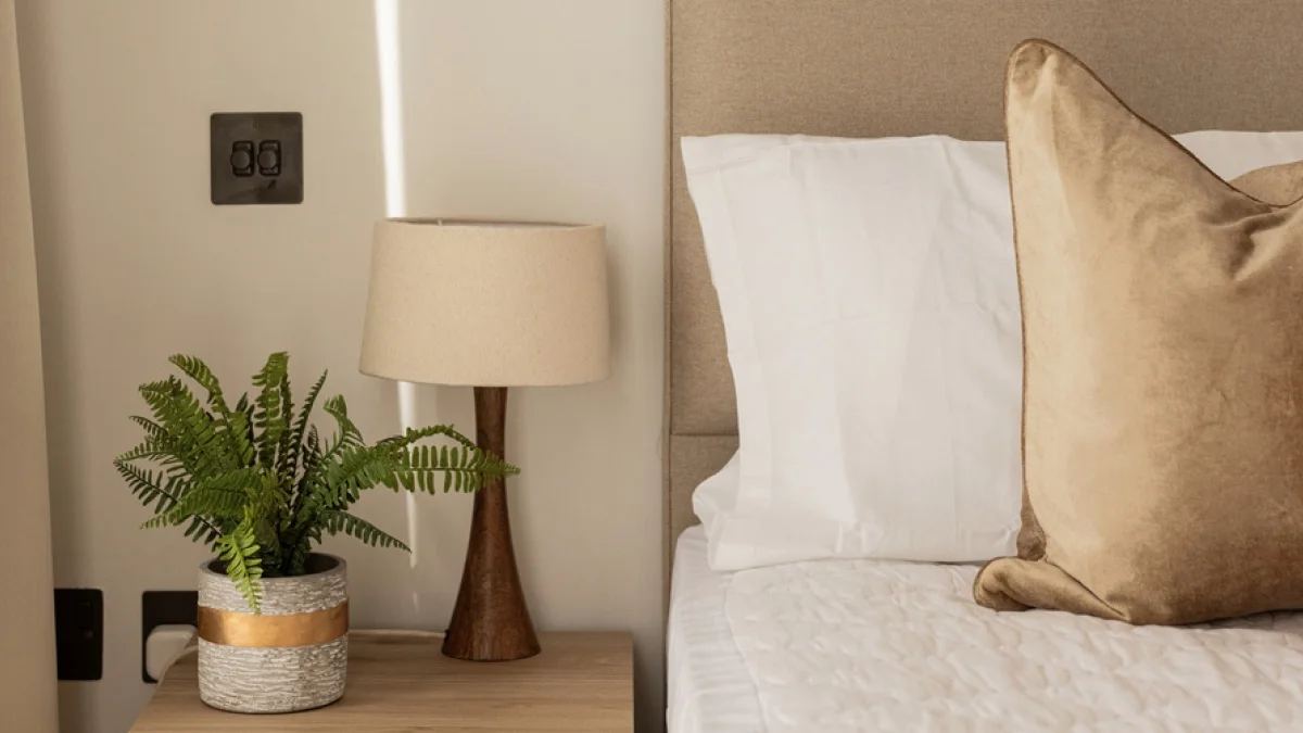 Airbnb bedroom detail featuring crisp white bedding, a bedside lamp and greenery for a comfortable and inviting guest stay.