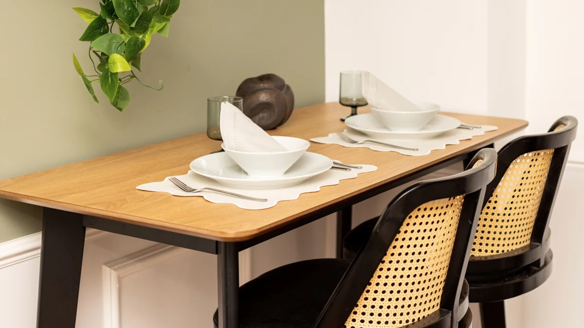 Stylish Airbnb dining area with a wooden table, coordinated place settings and cane-back chairs for guest comfort.