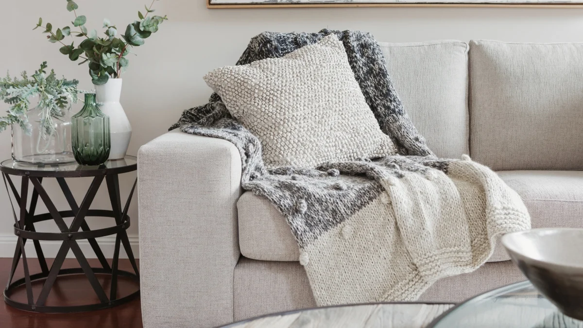Comfortable Airbnb living room with a neutral sofa, textured cushions and a soft throw creating a welcoming guest experience.