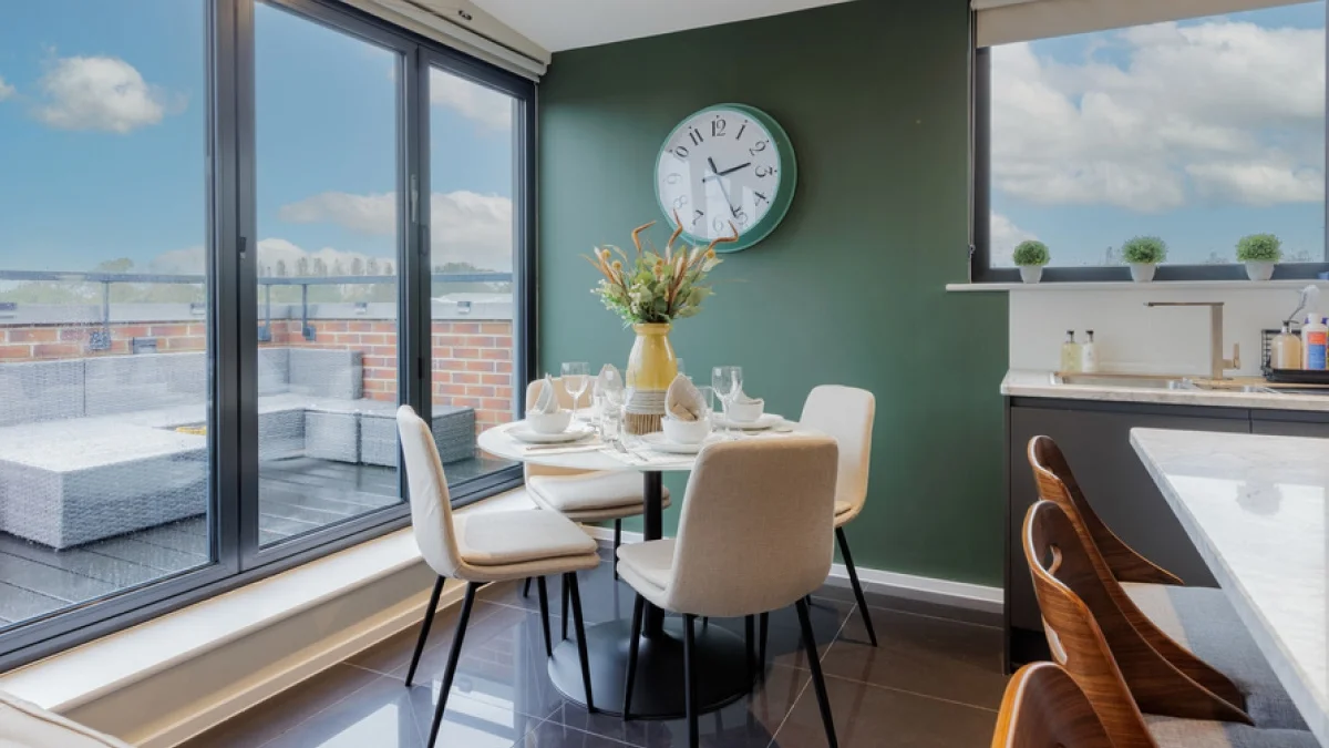 Furnished Airbnb dining area with a round table, neutral chairs and terrace views, creating an inviting space for short-term rental guests.