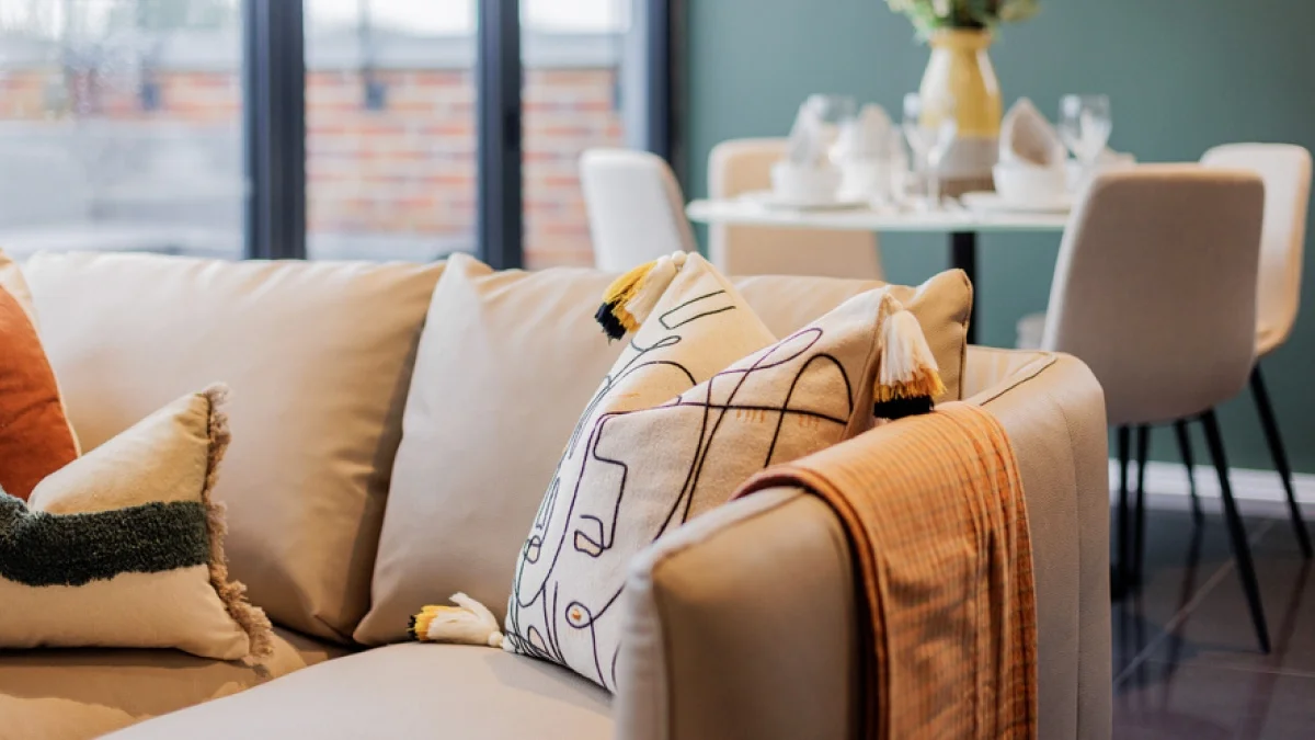 Airbnb living room with a neutral sofa, decorative cushions and a warm-toned throw to create a welcoming guest environment.