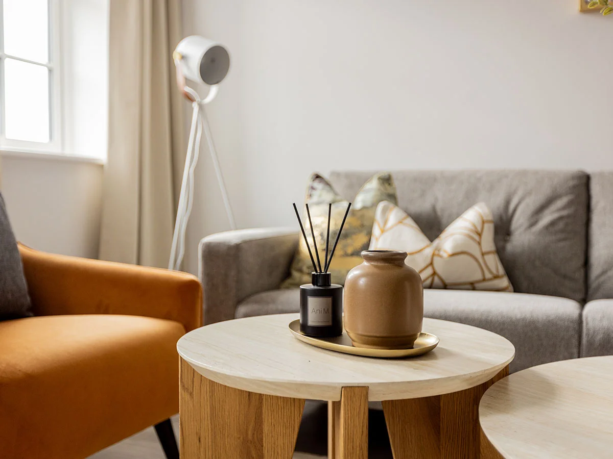 Coffee table styling in the living room of a furnished Horlicks Quarter apartment featuring decorative accessories, a grey sofa and an accent chair.