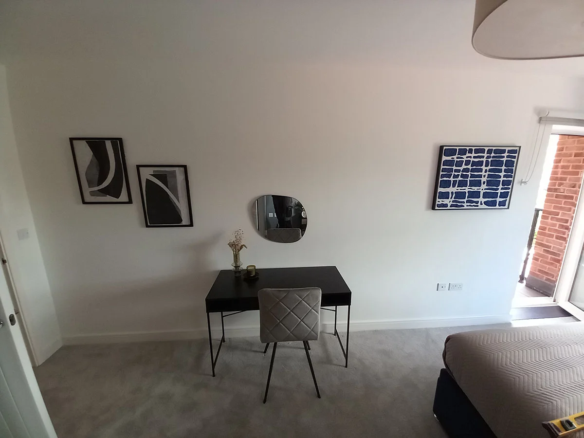 Bedroom with a modern study desk, upholstered chair, wall art and workspace in a furnished London apartment