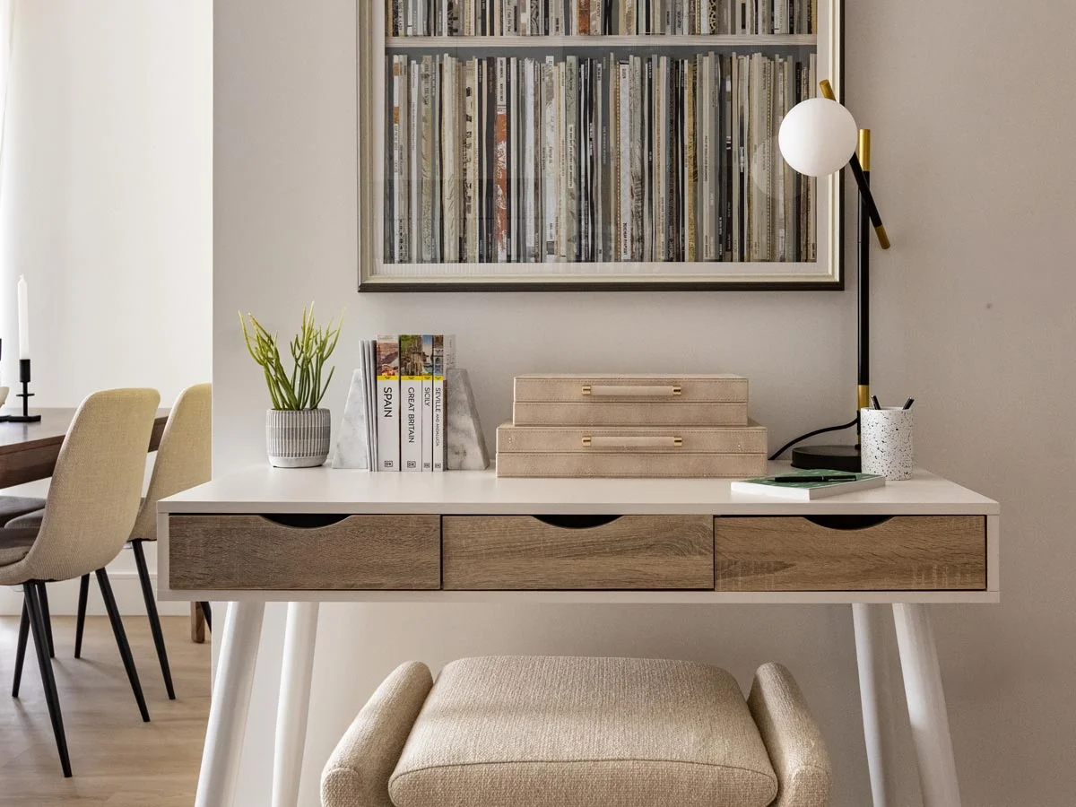 A compact home office study desk styled by InStyle Direct at Regents View, featuring a mid-century desk with wooden drawers, a cushioned stool, an arched modern lamp, and curated decorative bookends