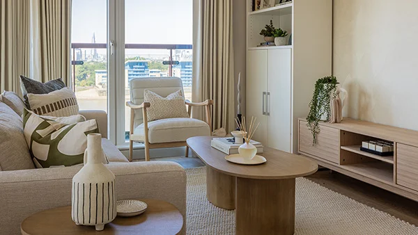 A contemporary living room furniture package curated by InStyle Direct at Seacon Tower, Canary Wharf, featuring a beige sofa with patterned cushions, an oval oak coffee table, and sliding glass doors revealing London skyline views