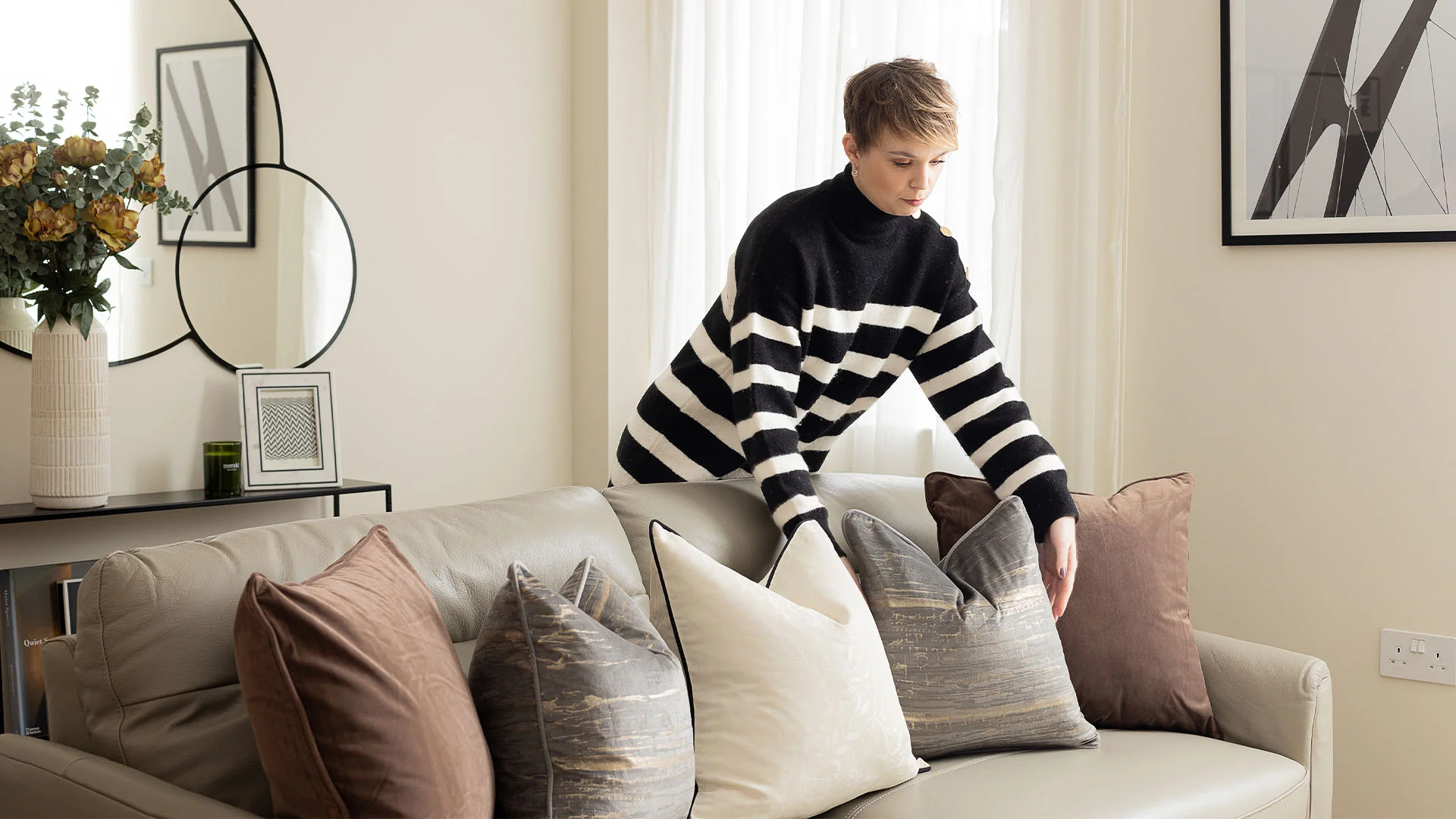 Interior designer arranging cushions in living room using gold furniture package setup
