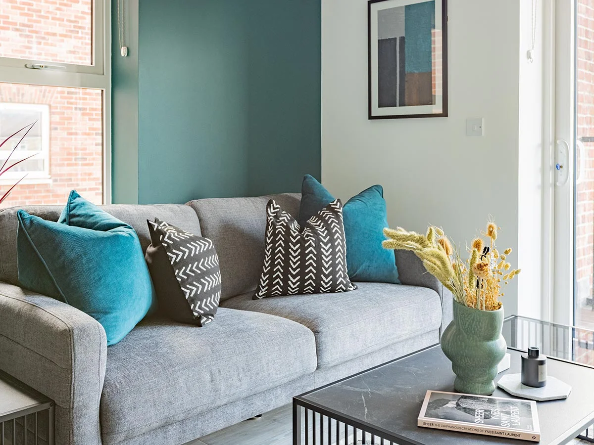 Contemporary living room with a grey sofa, colourful cushions, coffee table and decorative accessories in a furnished London property