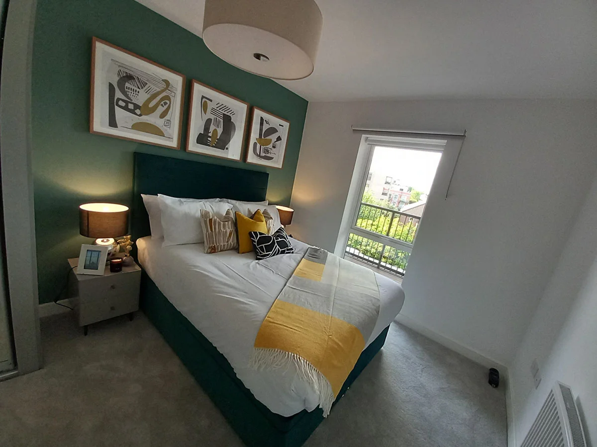 Modern master bedroom with a green feature wall, upholstered bed, abstract artwork and contemporary styling in a furnished London apartment.