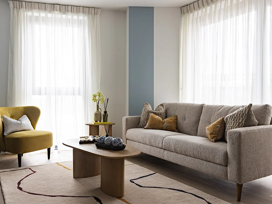Modern living room with textured sofa, mustard armchair, and soft neutral styling at Regents View