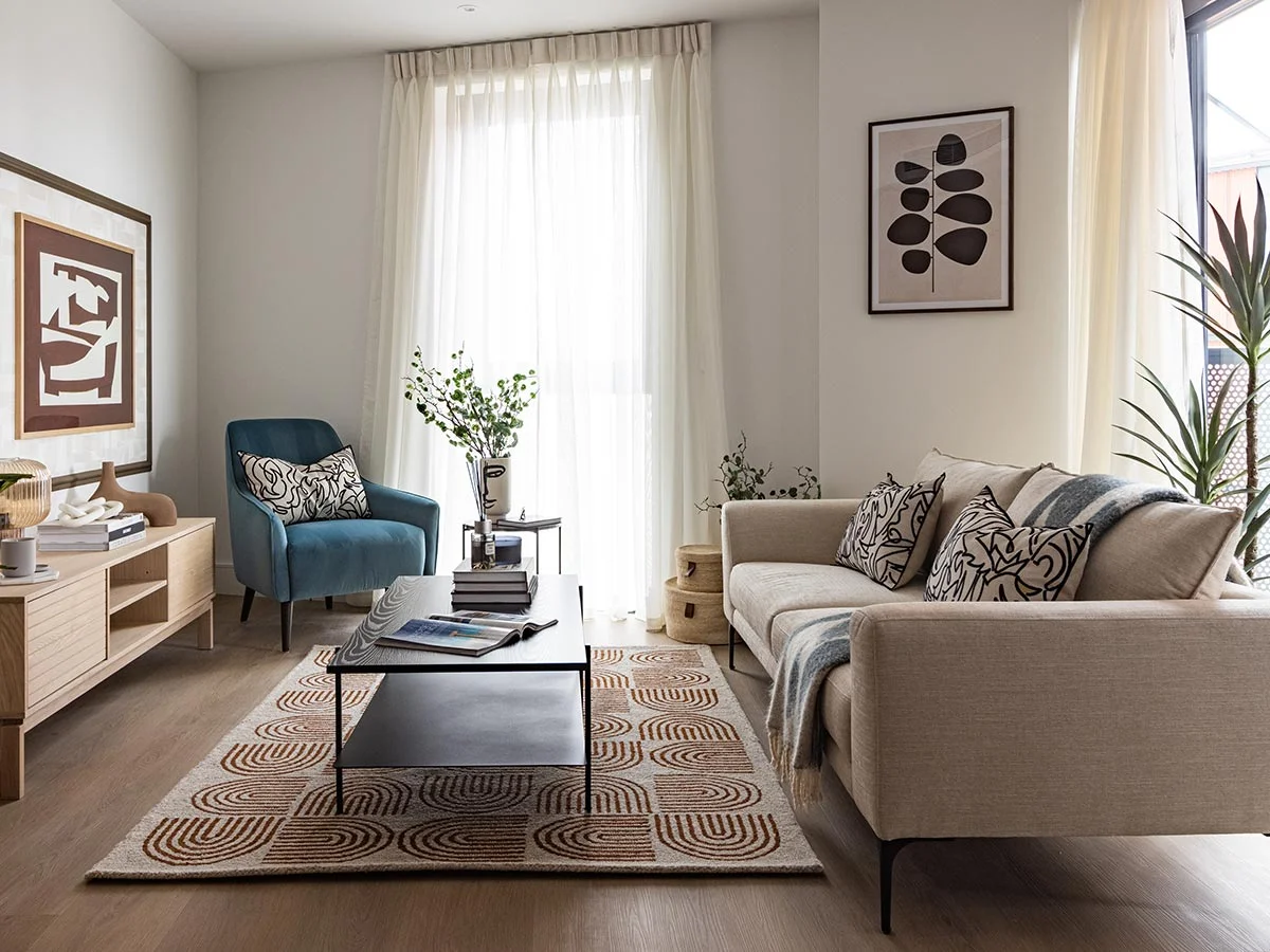 Contemporary living room featuring a neutral sofa, a vibrant blue accent armchair, a geometric patterned rug, and abstract wall art at Regent's View