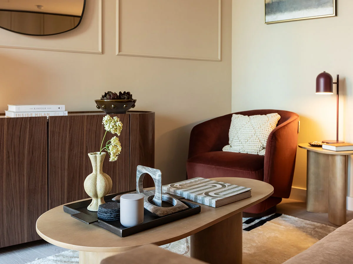 Stylish living room featuring a coffee table, accent chair, designer lighting, and curated décor at West End Gate